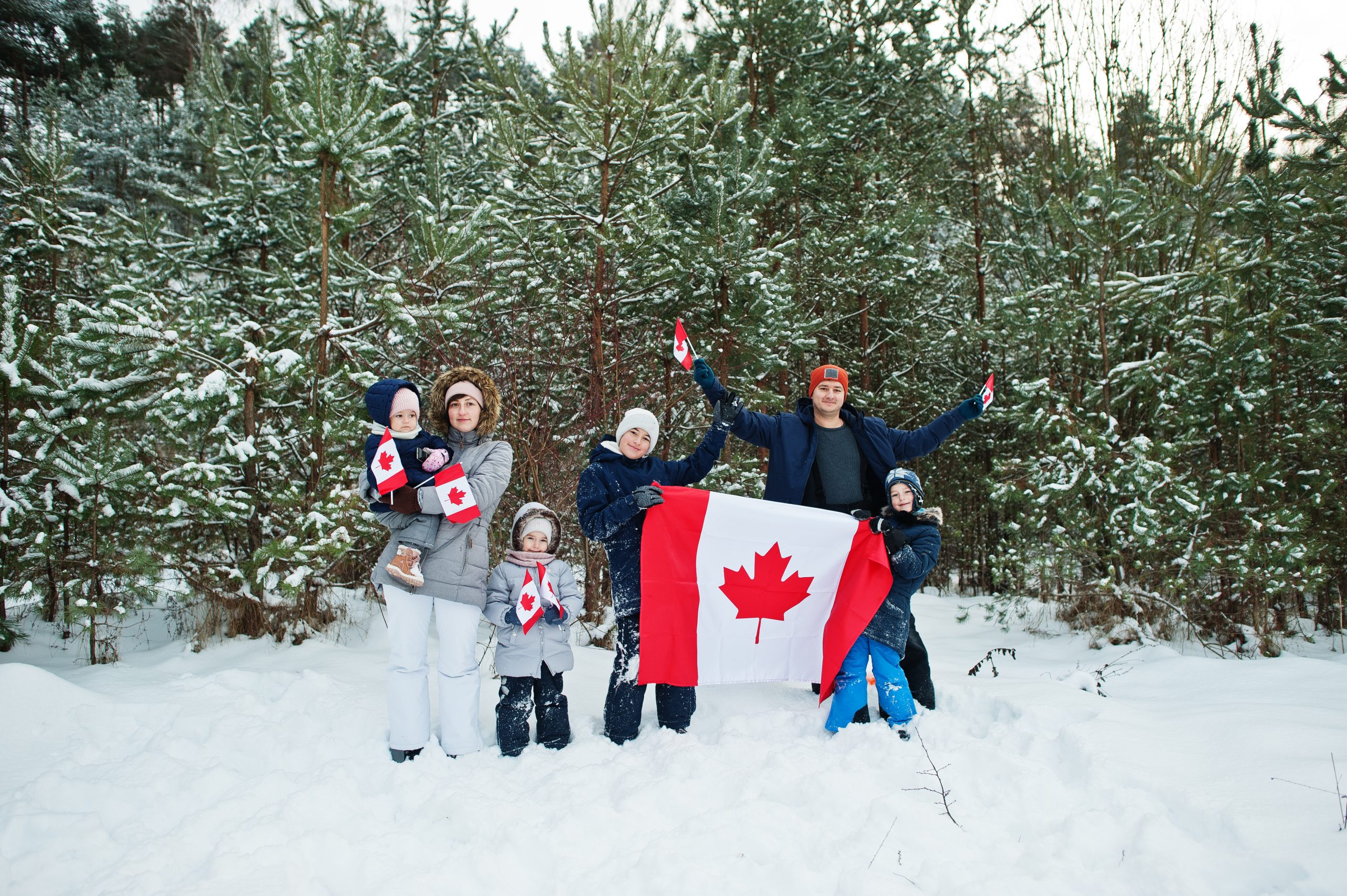 Family holding flag of Canada on winter landscape.