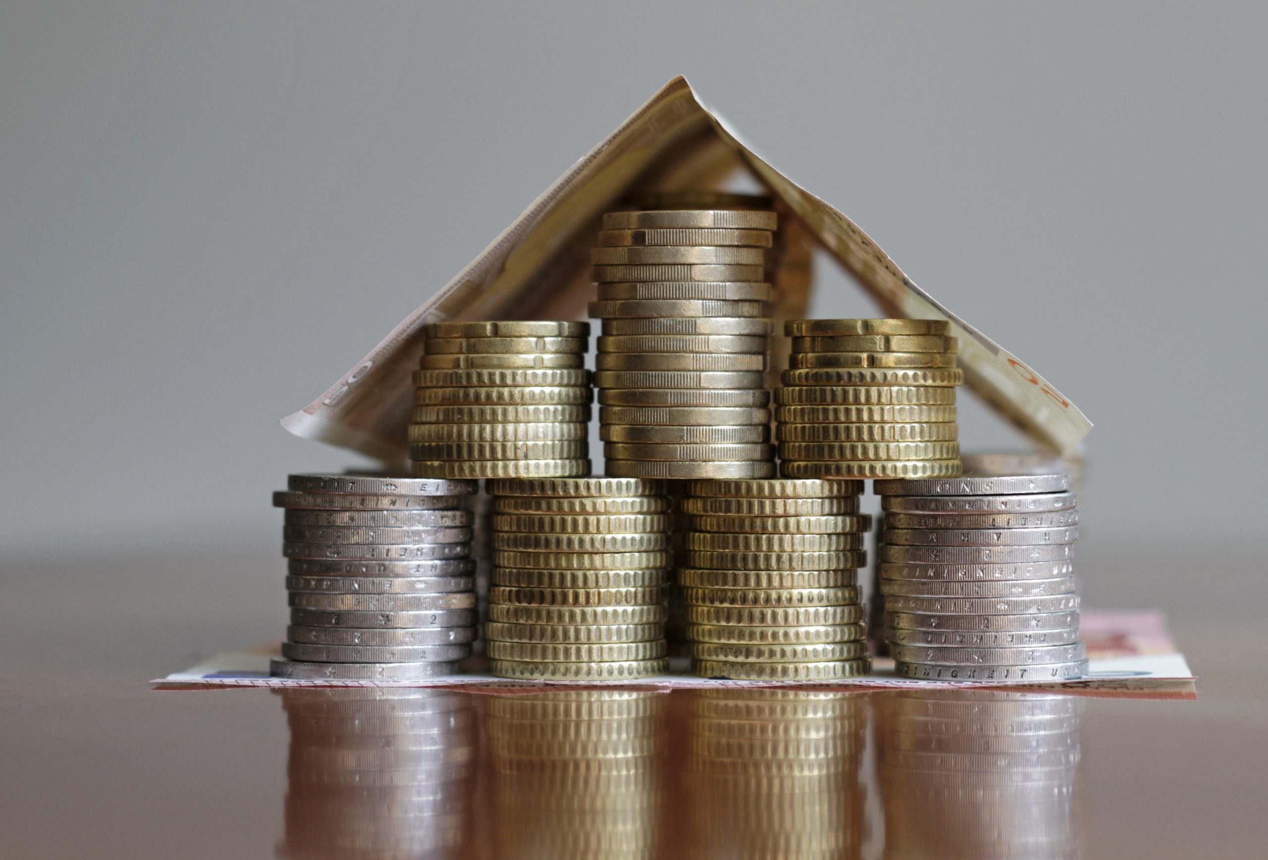 Selective focus shot of coins and bills shaped like a house